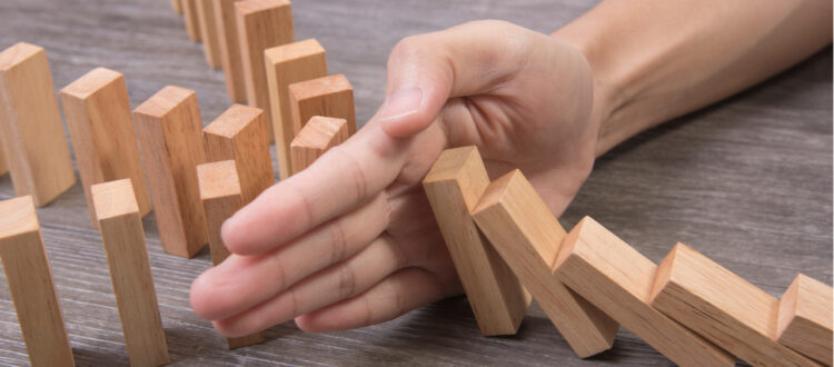 Hand stopping falling dominoes